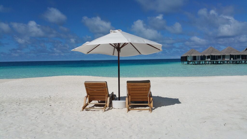 two chairs on a beach under an umbrella